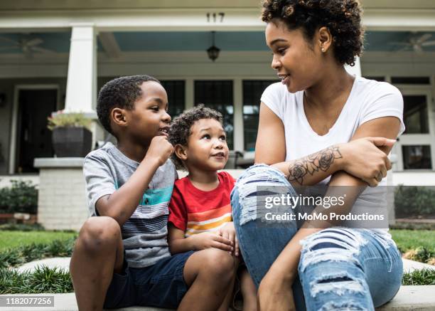 single mother playing with young sons in front of house - two kids playing with hose stock-fotos und bilder