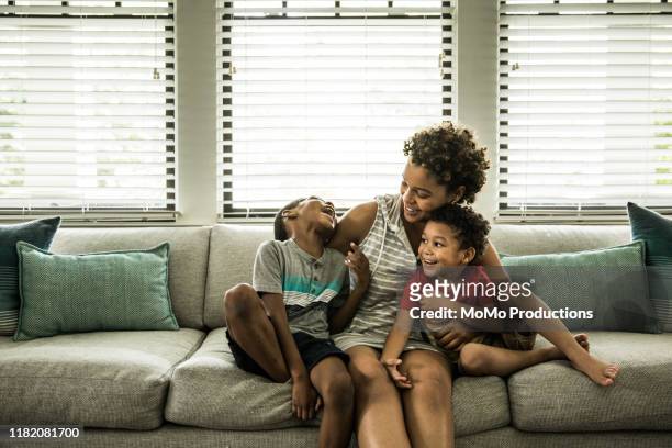single mother playing with young sons on couch - family with two children foto e immagini stock