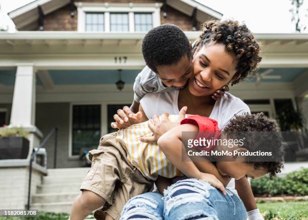 single mother playing with young sons in front of house - family home exterior stock-fotos und bilder