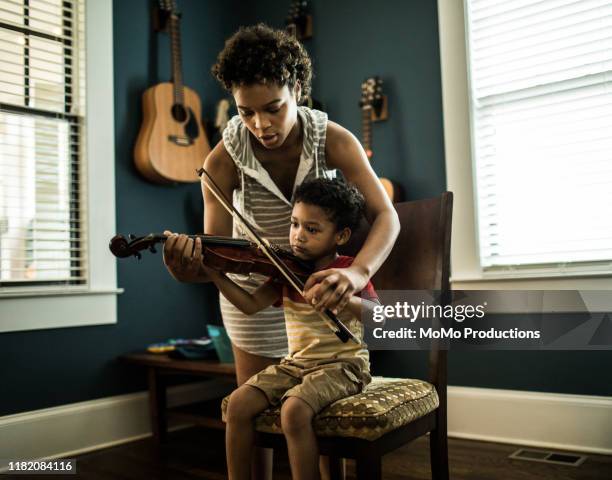 mother helping young boy (3 yrs) practice violin - boy violin stockfoto's en -beelden