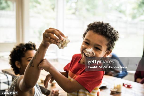 young boys with cake frosting on faces at party - food fight stock pictures, royalty-free photos & images