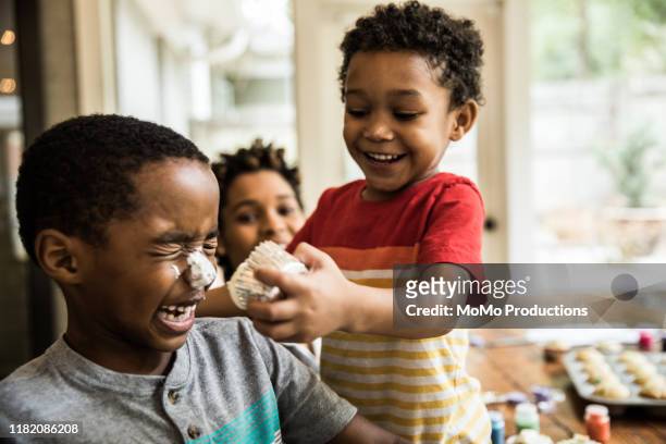 young boys with cake frosting on faces at party - children misbehaving stock pictures, royalty-free photos & images
