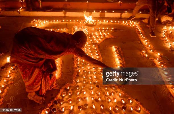An Indian woman decorates with earthen lamps on a ghat of the river Ganges during Dev Deepawali festival in Varanasi, India, 12 November, 2019. Dev...