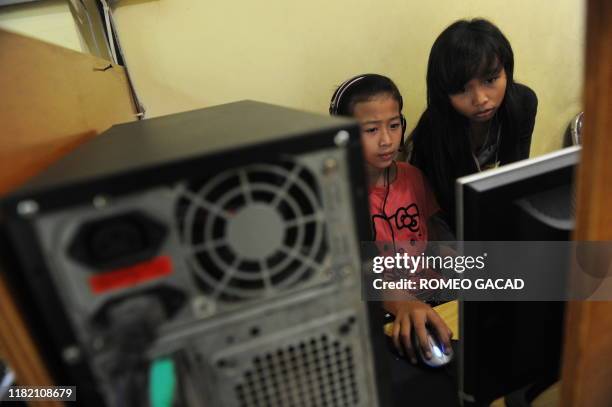 Two Indonesian 12 year old teenage girls Vinna Erviliana, and Mardiana go online on Facebook at an Internet shop in Jakarta on June 17, 2010....