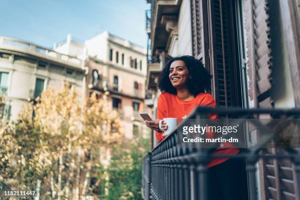 mujer de raza mixta en vacaciones de navidad en barcelona enviando mensajes de texto en la terraza - barcelona spain fotografías e imágenes de stock