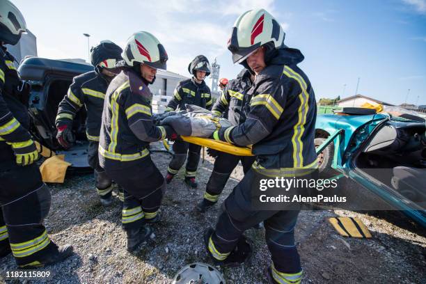 brandweerlieden in een reddingsactie bij een auto-ongeval met het slachtoffer - rescue worker stockfoto's en -beelden