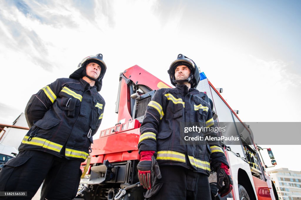 Porträt von zwei Feuerwehrleuten bei einer Rettungsaktion am Feuerwehrauto