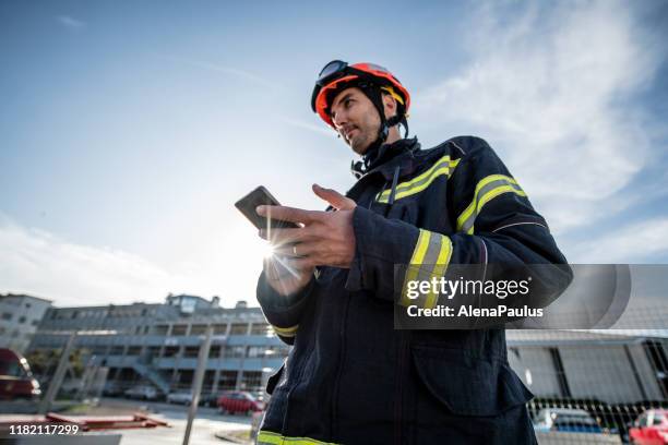 sapeurs-pompiers dans une formation d'opération de sauvetage, homme utilisant un téléphone intelligent - pompier photos et images de collection