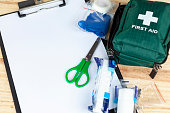 Green first aid kit on a table with a clipboard