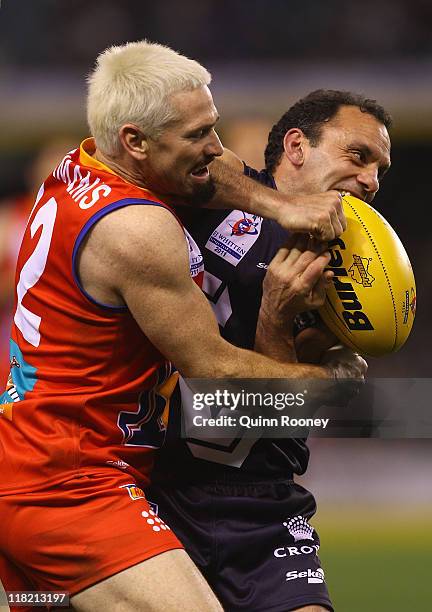 Tony Liberatore of Victoria handballs whilst being tackled by Jason Akermanis of the All Stars during the E.J Whitten Legends Game at Etihad Stadium...