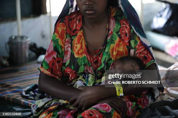 Woman who recently fled drought in Somalia holds her daughter in her arms at a clinic run by Doctors Without Borders at the worlds biggest refugee...