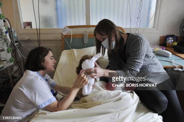 Anne-Laure de la Rochette présente à sa fille Itea, "Plume", une poupée, le 18 novembre 2010 au centre de gastroentérologie de l'hôpital Necker à...
