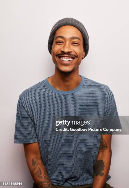 lächelnder junger mann mit tätowierungen vor grauem hintergrund - alternative lifestyle stock-fotos und bilder