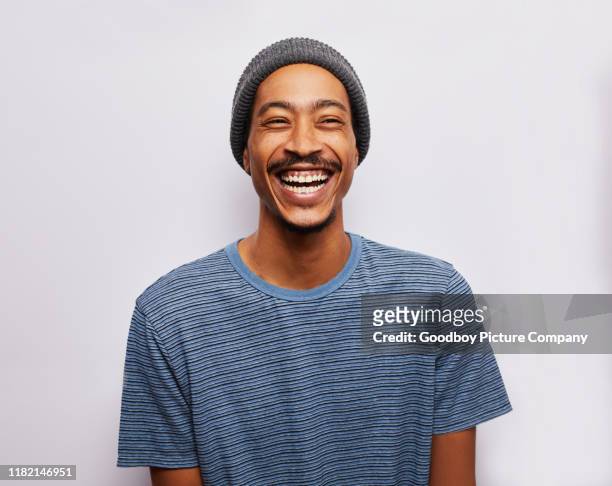 lachen jonge man staande tegen een grijze achtergrond - lachen stockfoto's en -beelden