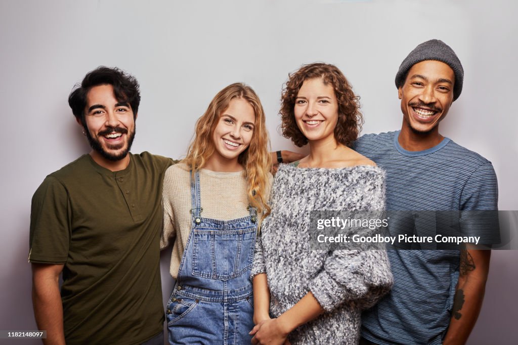 Lächelnde Gruppe von verschiedenen jungen Freunden vor grauem Hintergrund
