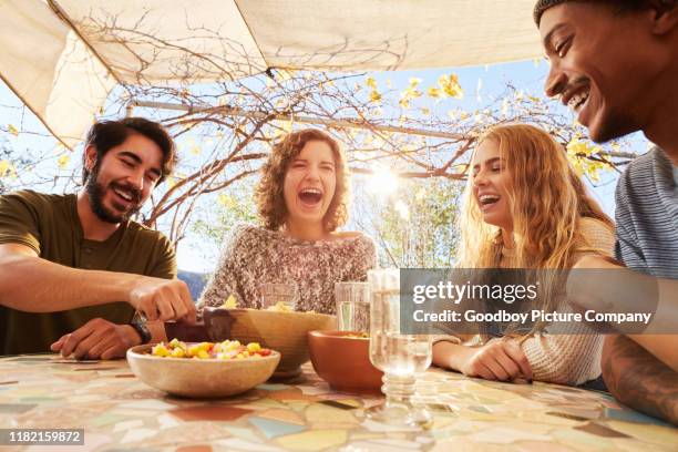 young friends laughing together while eating snacks outdoors - afternoon snack stock pictures, royalty-free photos & images