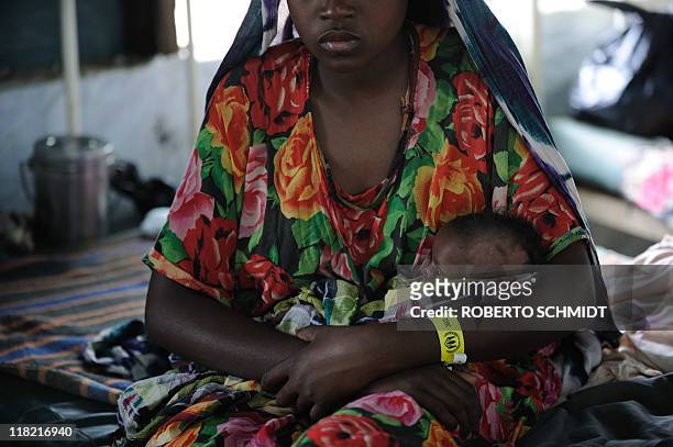 Woman who recently fled drought in Somalia holds her daughter in her arms at a clinic run by Doctors Without Borders at the worlds biggest refugee...