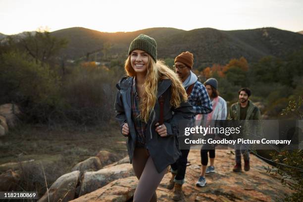 sonriendo joven y amigos caminando por una colina juntos - excursionismo fotografías e imágenes de stock