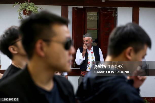 Man wearing traditional Serbian clothing as he welcomes Chinese tourists to take a part in a traditional Serbian wedding show for tourists in an...