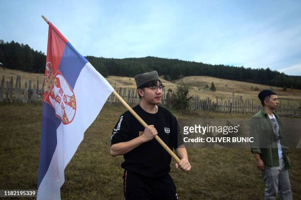 Chinese tourists wave Serbian flag as they take part in traditional Serbian wedding show for tourists in an ethno village Gostoljublje, near central...