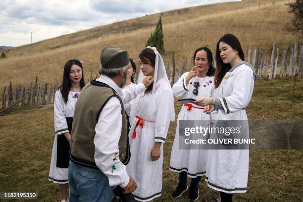 Chinese tourists wear traditional dresses as they prepare to take part in a Serbian wedding show for tourists in an ethno village Gostoljublje, near...