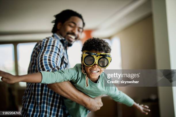 glücklicher schwarzer junge, der spaß mit seinem vater zu hause hat. - flying dad son stock-fotos und bilder