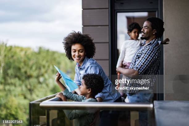famille afro-américaine heureuse appréciant sur un balcon. - balcony photos et images de collection
