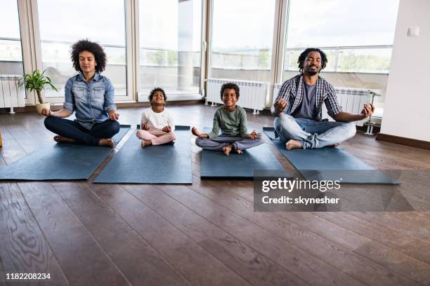 african american family meditating in lotus position in the apartment. - kids meditating stock pictures, royalty-free photos & images