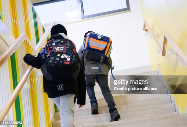 November 2019, Hamburg: Primary school children with their satchels and gym bags run down a staircase to their classroom at the Brüder-Grimm-Schule...