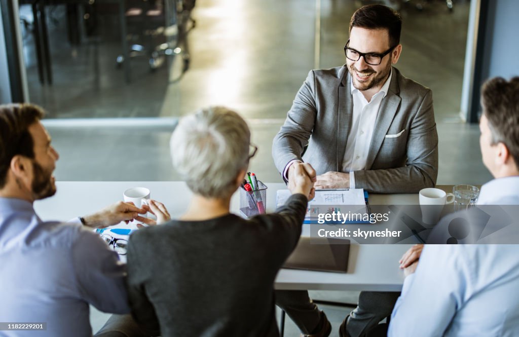 Un hombre de negocios feliz estrechando la mano del miembro del equipo de recursos humanos en la oficina.