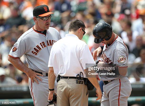 Aaron Rowand of the San Francisco Giants is hit by a pitch in the third inning and is checked on by head trainer Dave Groeschner and manager Bruce...