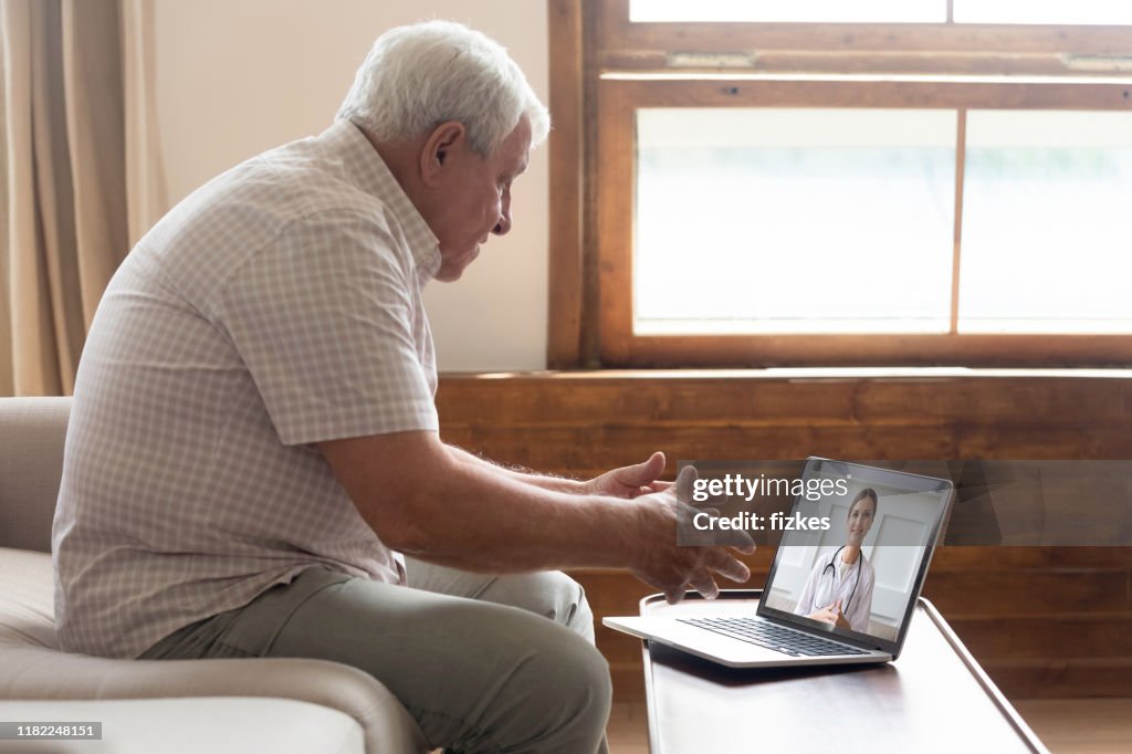 Elderly man make distant video call communicating with doctor online