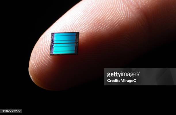 blue computer chip on tip of index finger - index finger fotografías e imágenes de stock