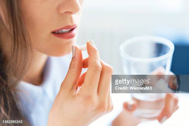 close up of woman taking pill - 止痛劑 個照片及圖片檔