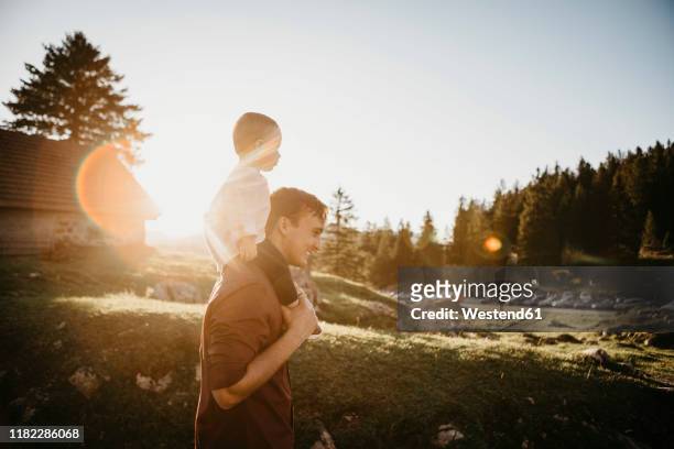 father carrying little son on shoulders on a hiking trip at sunset, schwaegalp, nesslau, switzerland - berghütte stock-fotos und bilder