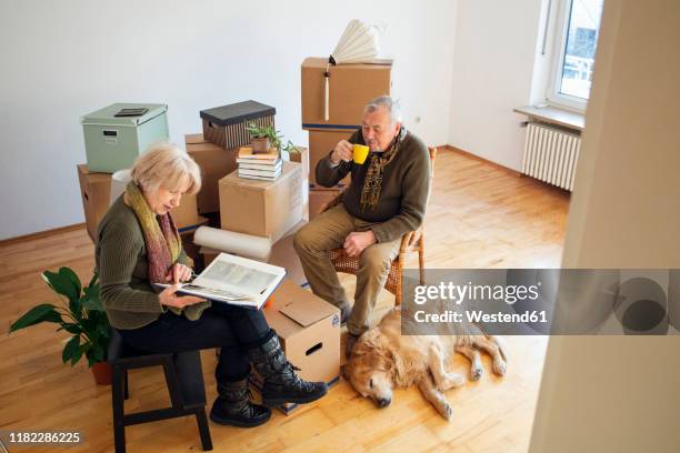 senior couple having a break surrounded by cardboard boxes in an empty room - coffee package stock-fotos und bilder