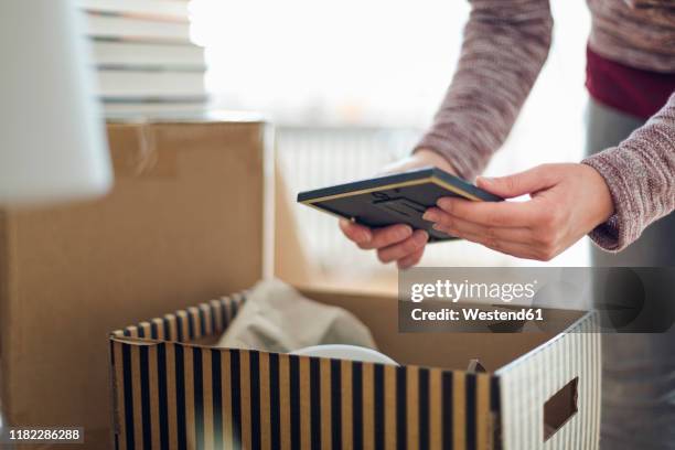 close-up of woman unpacking cardboard box in new home - memories box stock pictures, royalty-free photos & images