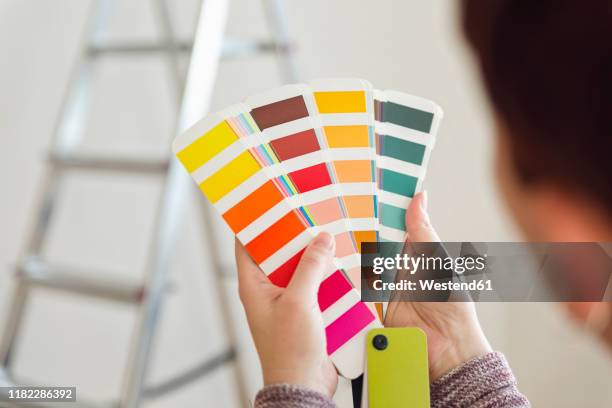 woman holding colour sample in an empty room with a ladder - color chart stock-fotos und bilder