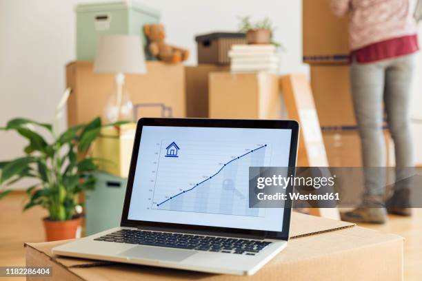 rising line graph on laptop screen in front of cardboard boxes in a new home - home economics ストックフォトと画像