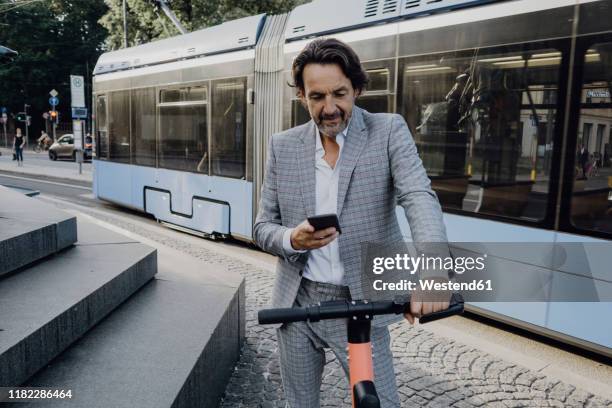 businessman renting an e-scooter in the city - movilidad sostenible fotografías e imágenes de stock