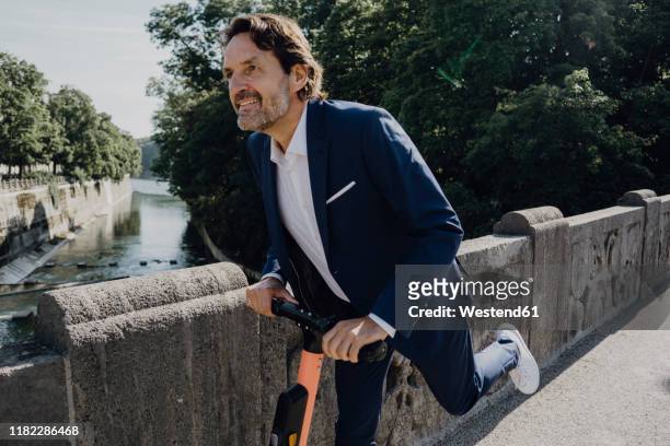 businessman with e-scooter on a bridge - active lifestyle stock-fotos und bilder