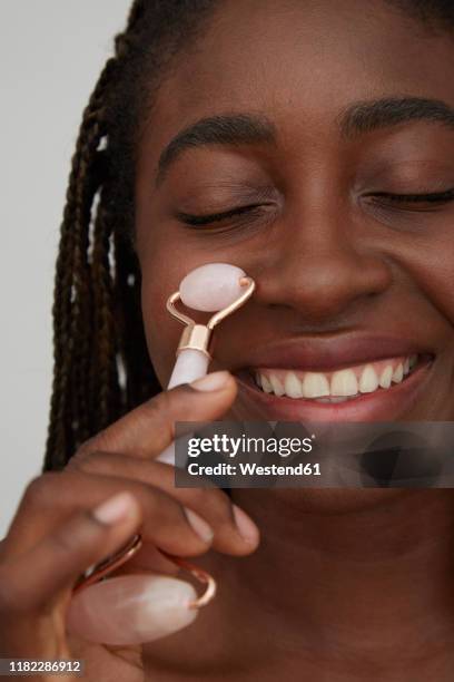 portrait of african woman using jade roller - 玉石滾輪 個照片及圖片檔