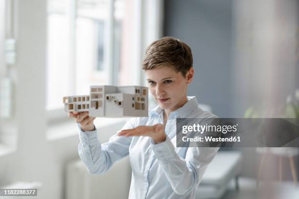 confident businesswoman holding architectural model in office - modelo arquitetônico - fotografias e filmes do acervo