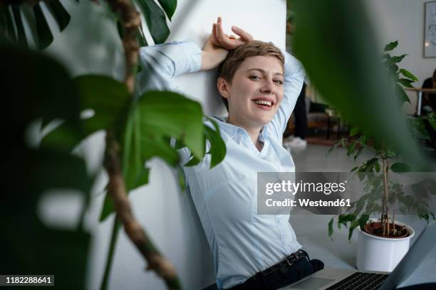 portrait of a businesswoman with laptop sitting on the floor surrounded by plants - bluse stock-fotos und bilder