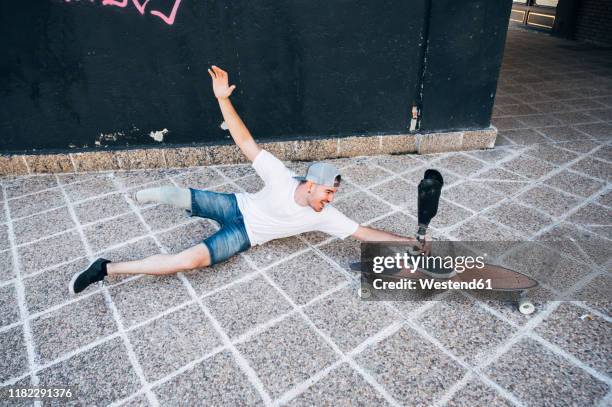 amputated young man having fun with leg prosthesis and skateboard - irony stockfoto's en -beelden