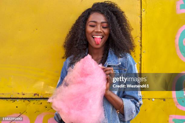 portrait of smiling young woman with pink candyfloss sticking out tongue - cotton candy stock pictures, royalty-free photos & images