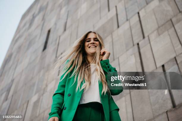 portrait of laughing young woman wearing green pantsuit, vienna, austria - low angle view stock pictures, royalty-free photos & images