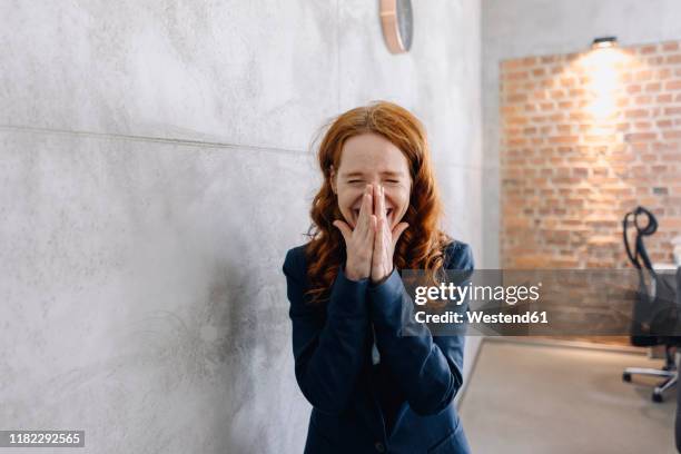 laughing redheaded businesswoman in office - laughing stock-fotos und bilder