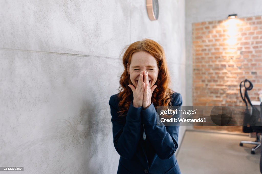 Laughing redheaded businesswoman in office