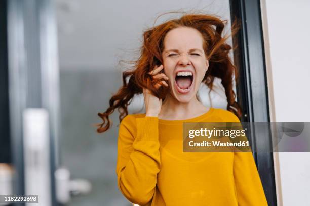 screaming woman with windswept hair in office - women shouting stock pictures, royalty-free photos & images